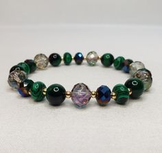 "The bracelet is made of crystals, glass, and gemstones and is beautifully handcrafted. Featuring vibrant crystal beads, malachite stone, green tiger eye, and 14 kt gold plated accent beads. With its versatile bead assortment, this bracelet goes with any outfit. You will be able to show off your unique style and make your wrist the center of attention. Most of my bracelets fit wrists between 6\" and 6.5\" in size. Before placing an order, please confirm your size. Thank you" Handmade Malachite Beaded Bracelets For Spiritual Use, Handmade Malachite Spiritual Beaded Bracelets, Crystal Bracelet With Gemstone Beads, Spiritual Faceted Beads Crystal Bracelet For Jewelry Making, Spiritual Crystal Beaded Bracelets For Healing, Crystal Gemstone Beaded Bracelets, Elegant Beaded Bracelets With Gemstone Czech Glass Beads, Elegant Czech Glass Beaded Bracelets With Gemstone, Malachite Beaded Bracelets As Gift