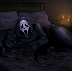 a person in a ghost mask laying on a bed with candles behind them and a black cloth draped over their head