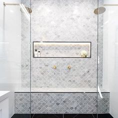 a white tiled bathroom with glass shower doors