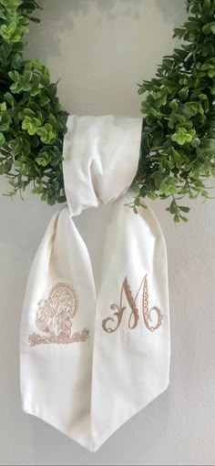 the monogrammed scarf is hanging on the wall next to some green leaves and branches