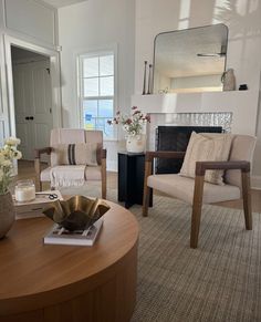 a living room with two chairs and a table in front of a mirror on the wall