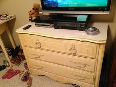 a tv sitting on top of a dresser next to a pair of shoes and a teddy bear