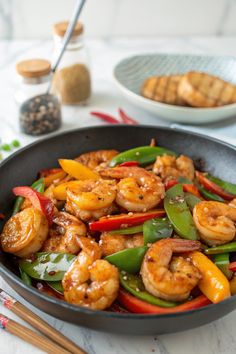 a skillet filled with shrimp, peppers and green beans on top of a table