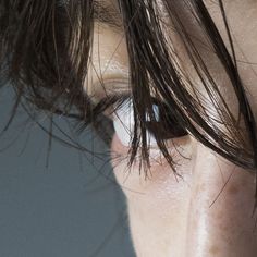 a close up of a person's eye with wet hair