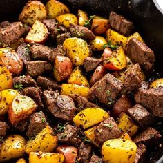 cooked potatoes and meat in a skillet with herbs on top, ready to be eaten