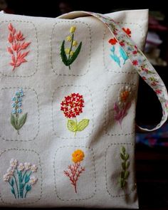 a white bag with embroidered flowers on it