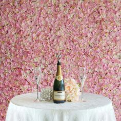 a table topped with a bottle of champagne next to two wine glasses and a bouquet of flowers