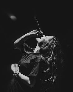 a woman with long hair holding a violin in her right hand and looking up at the sky