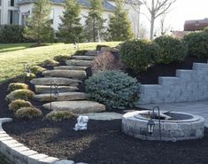 a stone fire pit in the middle of a yard with steps leading up to it