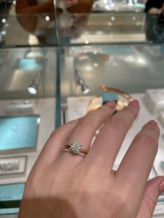 a woman's hand with a ring on it in front of a display case