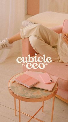 a man laying on top of a pink couch next to a table with a book