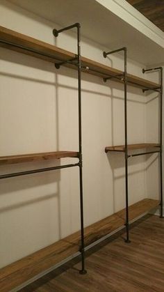 an empty walk in closet with wooden shelves and metal pipe shelvings on the wall