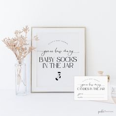 a baby socks in the jar sign next to a vase with flowers and a card