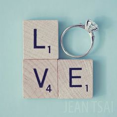 a wooden block with the word love spelled on it and a ring resting on top