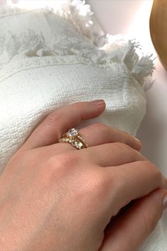 a woman's hand with a ring on it and a white towel in the background