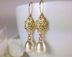 a pair of earrings with pearls hanging from them