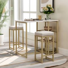 two stools in front of a table with flowers on it and a potted plant