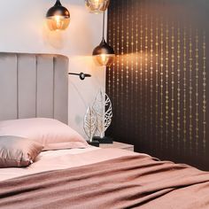 a bed with two lamps on either side of it and a pink comforter in front of the headboard