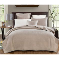 a bed with a white comforter and pillows