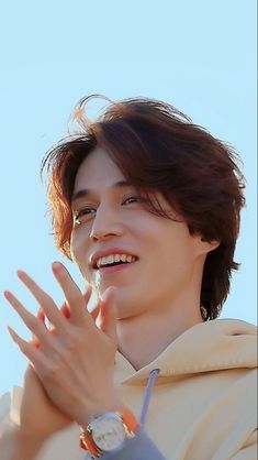 a young man with his hands together in front of the camera, smiling and clapping