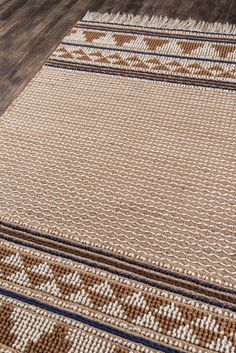 a brown and white area rug with blue trimmings on the bottom, sitting on a wooden floor