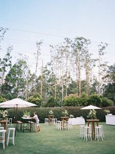 a person sitting at a table in the middle of a field with chairs and umbrellas