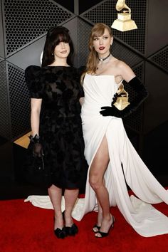 two women standing next to each other on a red carpet