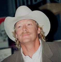 a man wearing a white cowboy hat with long blonde hair and a moustache on his face