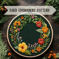 an embroidery pattern with flowers and leaves in the center, surrounded by pine needles on a wooden surface