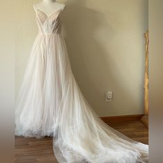 a wedding dress is displayed on a mannequin in front of a white wall