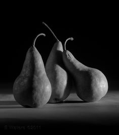 three pears sitting side by side in black and white with the dark background behind them