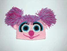 a crocheted pink and purple hat with big eyes