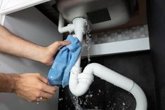 a man is washing his hands under a sink with a blue towel and water coming out of the faucet