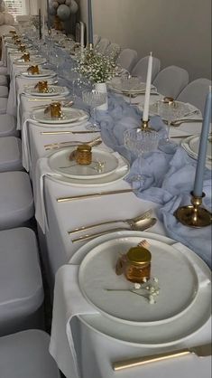 a long table is set with white plates and silverware