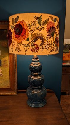 a lamp that is sitting on top of a wooden table next to a framed painting