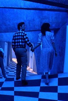 a man and woman holding hands while standing in a room with checkered flooring