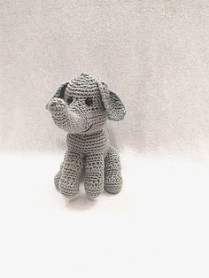 a small crocheted dog sitting in front of a white background