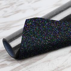 a black and silver glitter wrapping paper on a marble surface