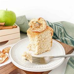 a piece of apple cake on a plate with a fork next to it and an apple in the background