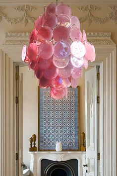 a living room filled with furniture and a fire place under a pink chandelier