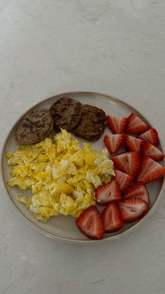 a plate with eggs, strawberries and cookies on it sitting on a white table