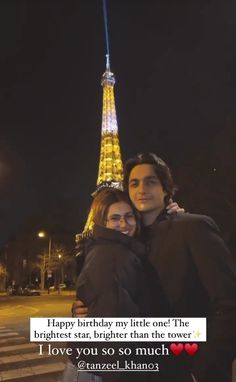 a man and woman standing next to each other in front of the eiffel tower