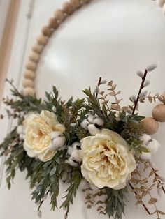 a flower arrangement is displayed on a white wall in front of a beaded necklace