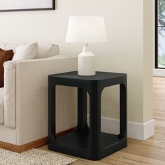 a living room with a white couch and black end table