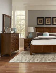 a bedroom scene with focus on the bed and dressers in the foreground, along with hardwood flooring