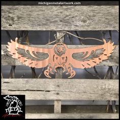 a wooden bench with a metal bird on it's back and the seat is made out of wood