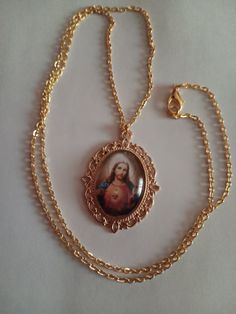 An ornate oval gold-tone pendant frames a lovely depiction of the Sacred Heart of Jesus.  The pendant measures 1 inch by 3/4 of an inch.  The chain (18k gold plated over stainless steel) can be ordered in 16", 18" 20" 22" or 24". Gold Oval Pendant Jewelry, Gold Nickel-free Oval Pendant Jewelry, Nickel-free Gold Oval Pendant Jewelry, Gold Jewelry For Valentine's Day, Oval Gold Jewelry For Valentine's Day, Gold Oval Jewelry For Valentine's Day, Gold Oval Pendant Locket Necklace, Nickel Free, Gold Oval Pendant Necklace Nickel Free, Nickel Free Gold Oval Pendant Necklace