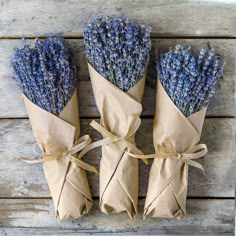 three bundles of dried lavender flowers tied to brown paper wrapped in twine on wooden planks