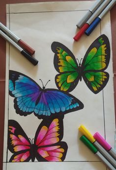 some crayons are laying on top of a piece of paper with butterflies painted on it