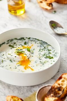 a white bowl filled with soup next to toasted bread on a marble counter top